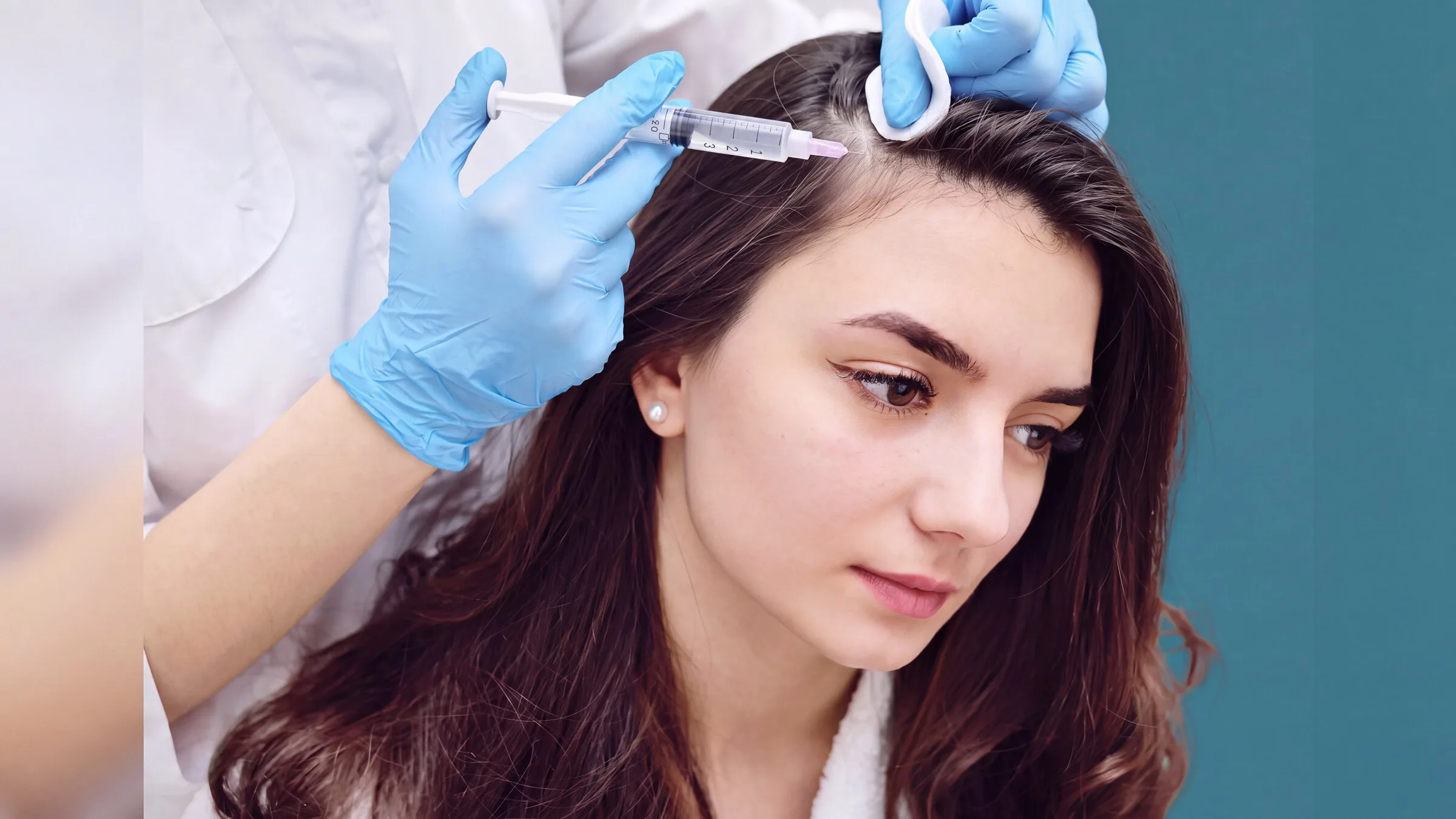 A seated patient receiving a fine injection along an exposed scalp part line during a hair restoration treatment