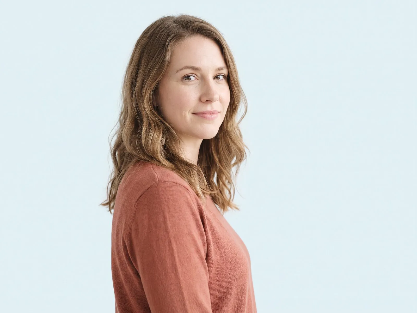 A woman photographed plainly against a pale azure ground, illustrating the hormone timeline beside her