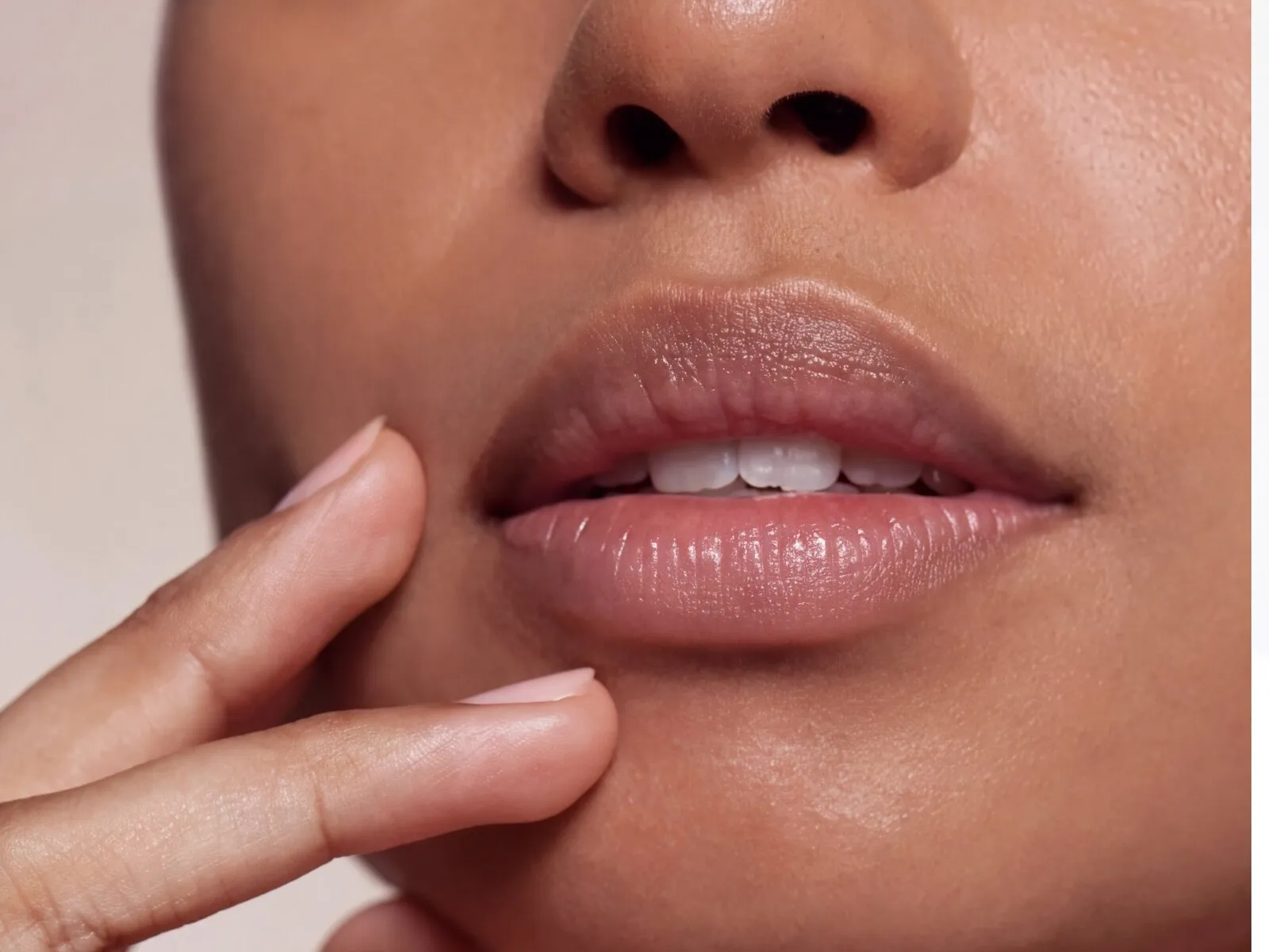 Naturally full, softly defined lips on a woman’s lower face with her fingertips at her chin, the area LipLase warms, without injections
